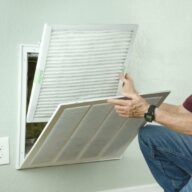 Man changing air filter in wall vent