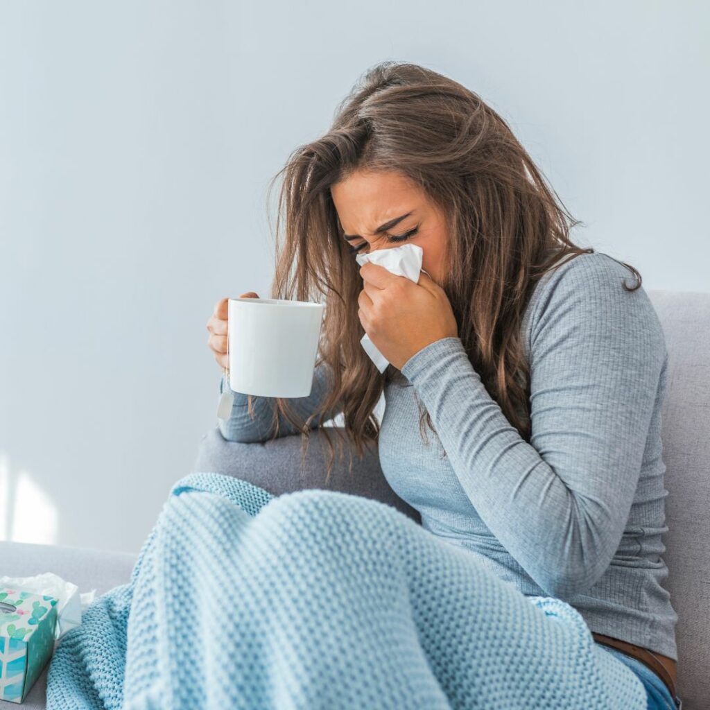 Person with a cold in a blanket and holding a mug