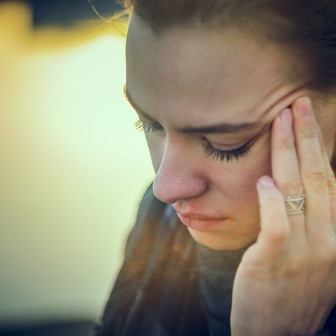 woman looking down pushes on temple with her fingers