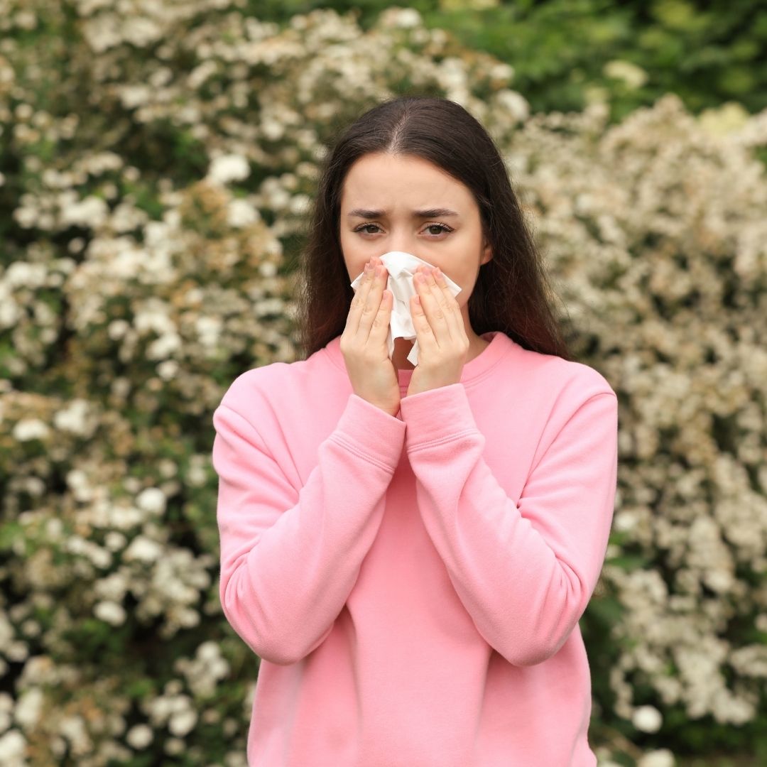 woman in park blowing her nose